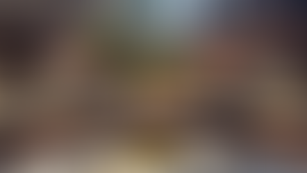 Dreamlike installation space with water-like light reflections covering walls and seating, soft curved forms, and a single tree at the centre creating contrast between movement and stillness.