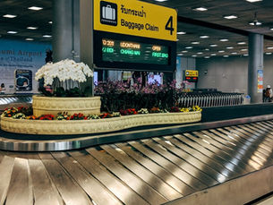 An empty luggage carousel at an airport with flowers in the centre island