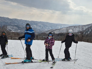 A family on skis at Hakuba's Tsugaike Kogen with mountains in the background