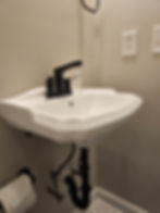Modern wall-mounted sink with black faucet.