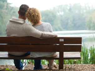 A couple sitting on a bench looking at a lake