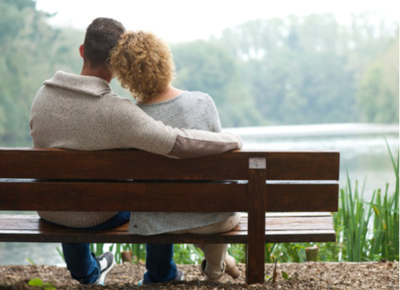 A couple sitting on a bench overlooking a lake