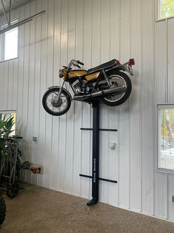 a classic motorcycle stored on a lift attached to the wall