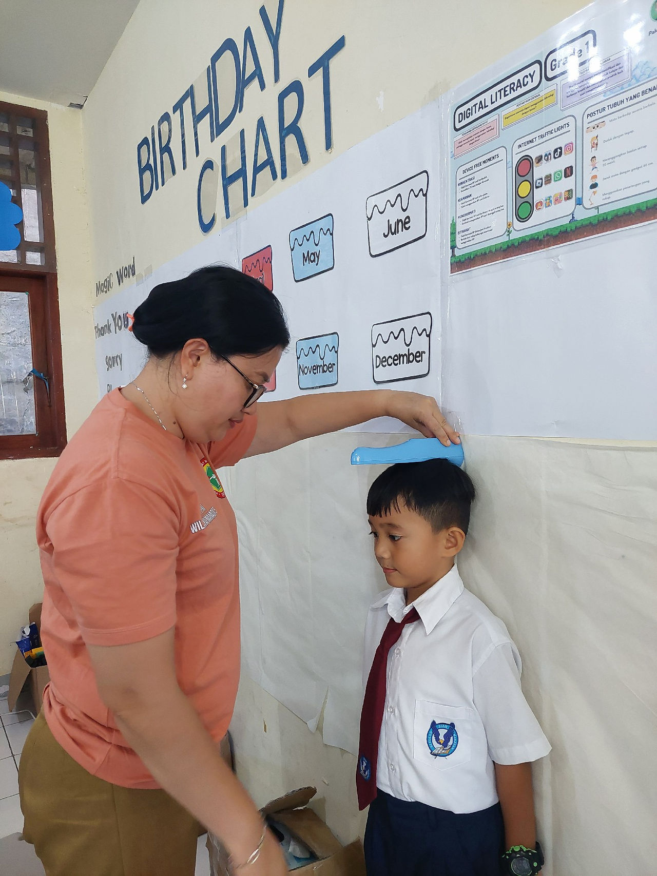 siswa kelas 1 SD yang tersenyum saat mengukur tinggi badannya di acara penjaringan kesehatan.