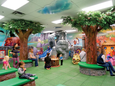 Indoor Zoo-Themed Play Area: A forest-themed indoor play area with large artificial trees, rock formations, and colorful animal characters, providing a creative and interactive environment for children.