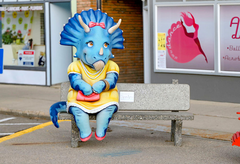A female blue triceratops dinosaur in a frilly yellow dress, sitting on a bench.