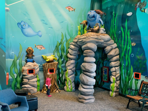 Underwater-Themed Play Area: A sea-life-themed indoor play area featuring a stone archway, sea animals, and interactive play stations, creating an immersive underwater experience for young visitors.