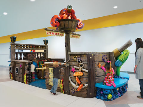 Pirate Ship Play Area: A pirate ship-themed play area with a large octopus sculpture perched on top of the mast. Children interact with various sections of the ship, designed for an immersive adventure play experience.