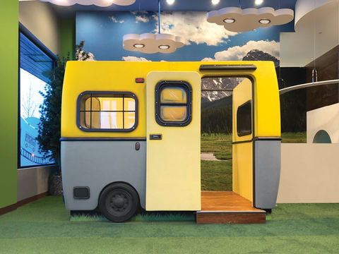 Camper-Themed Play Structure: A bright yellow camper-themed play structure, offering a whimsical and adventurous area for kids to explore in an indoor play setting.