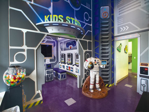 Space Station-Themed Play Area: A space-themed indoor play area with a futuristic design, including a space station, control panels, and an astronaut statue, offering an imaginative space exploration experience for kids.