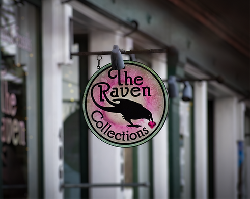 A street sign with the logo for the Raven Collections restore windows in the background