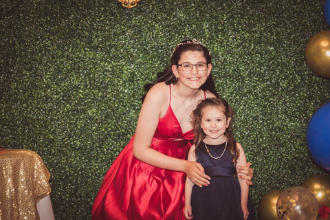 a girl in a red dress stands next to a little girl in a blue dress