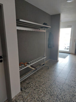 Flur mit Garderobe, Regalen und Fenster, graue Wände, helle Böden, Die Kapellenschule