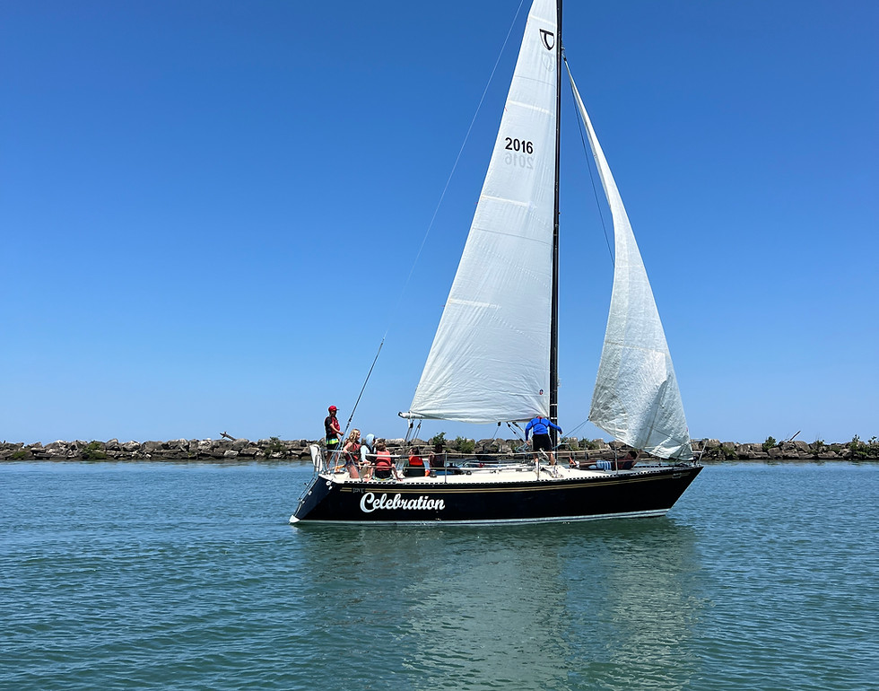 A sailboat with white sails on calm blue water under a clear sky
