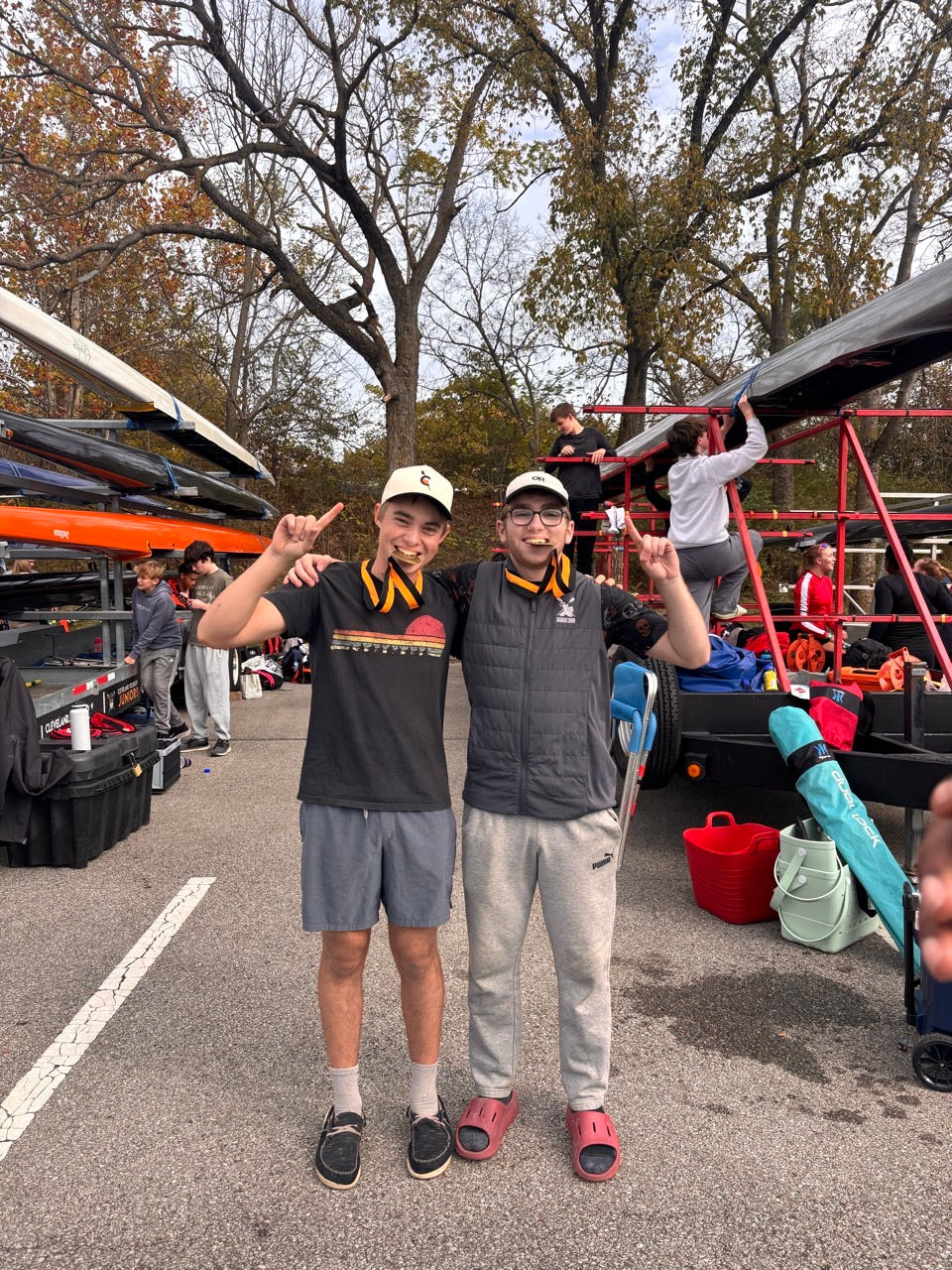 Two students pointing to medals at a high school rowing event.