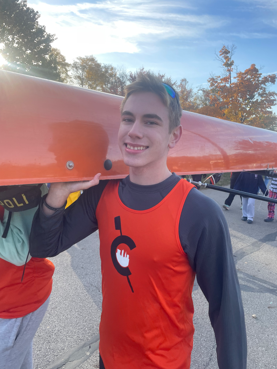 Smiling CFJ High School student carrying orange boat
