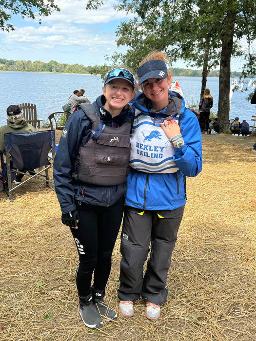 Two smiling women in life vests by a lake