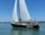 Evolution sailboat on calm blue water with people