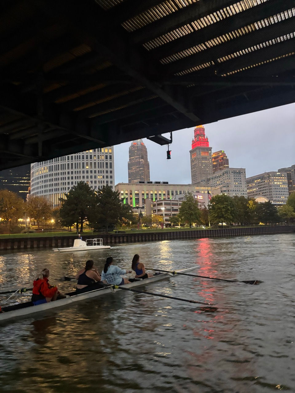Rowing team on river under bridge with city skyline