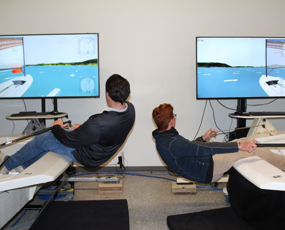 Two people using sailing simulators with large monitors