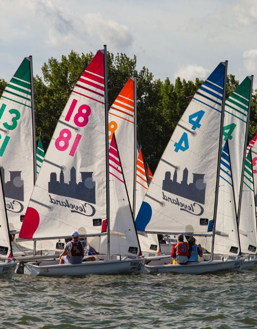 Line of small sailboats with red, green, blue numbered sails