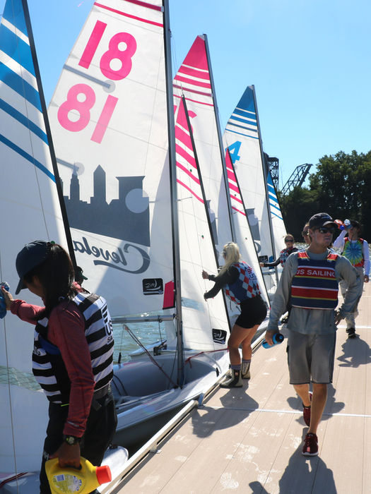 Group preparing small sailboats on a sunny dock
