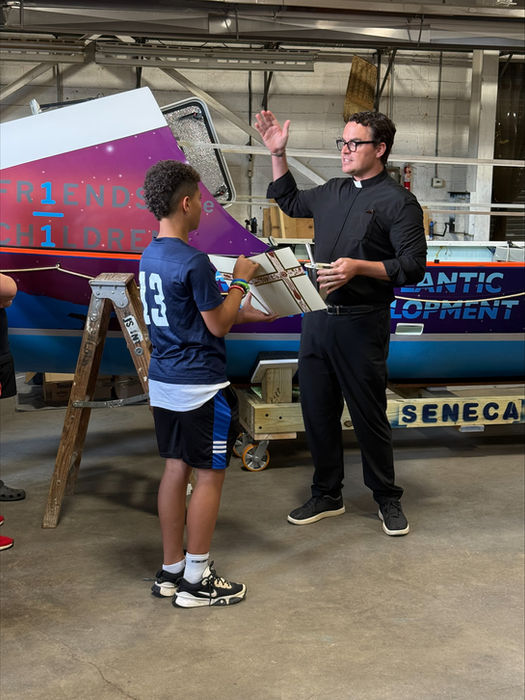 Man talks to boy in blue jersey near boat
