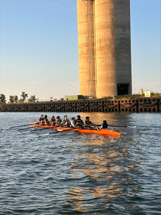People paddling orange kayaks on water near concrete tower