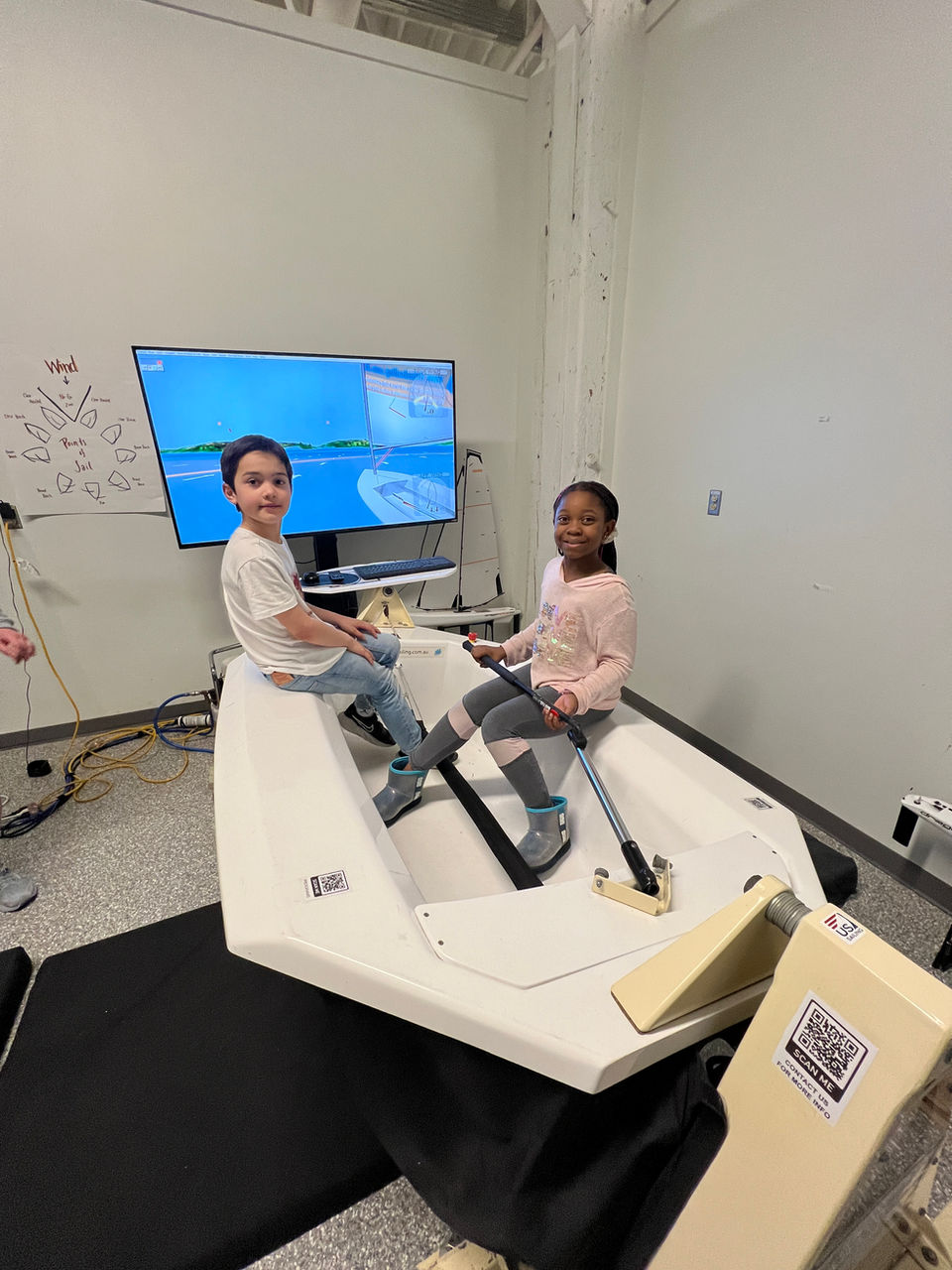 Two children operating a sailing simulator