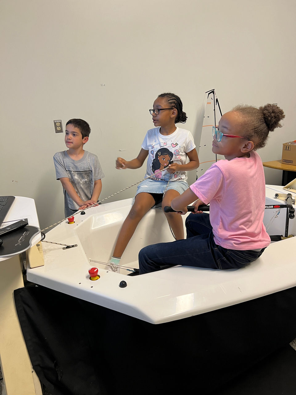 Three children interacting with a sailing simulator