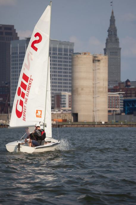 Person sailing a small boat in front of a city skyline