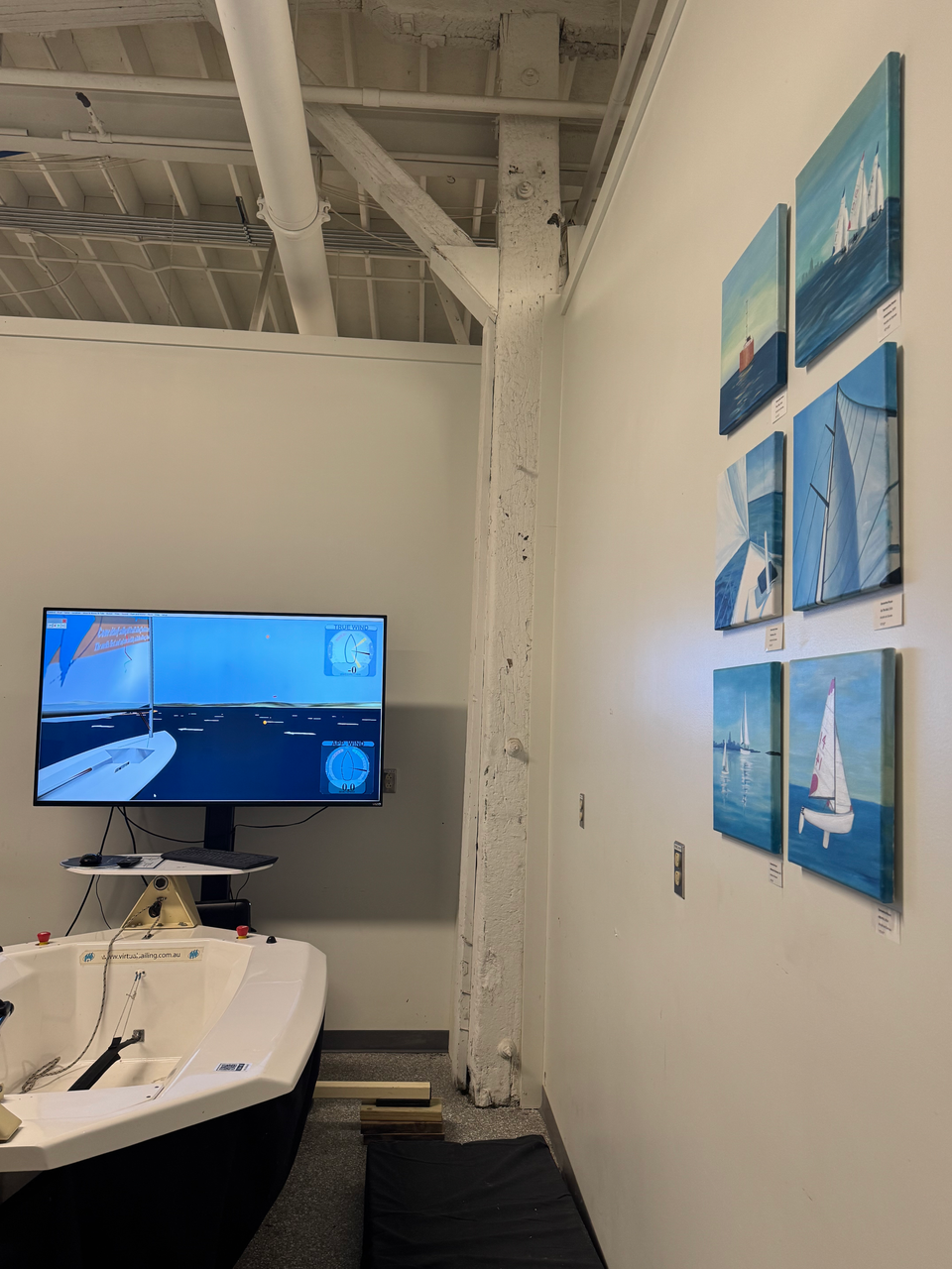 Sailing simulator with boat and screen, six sailboat paintings