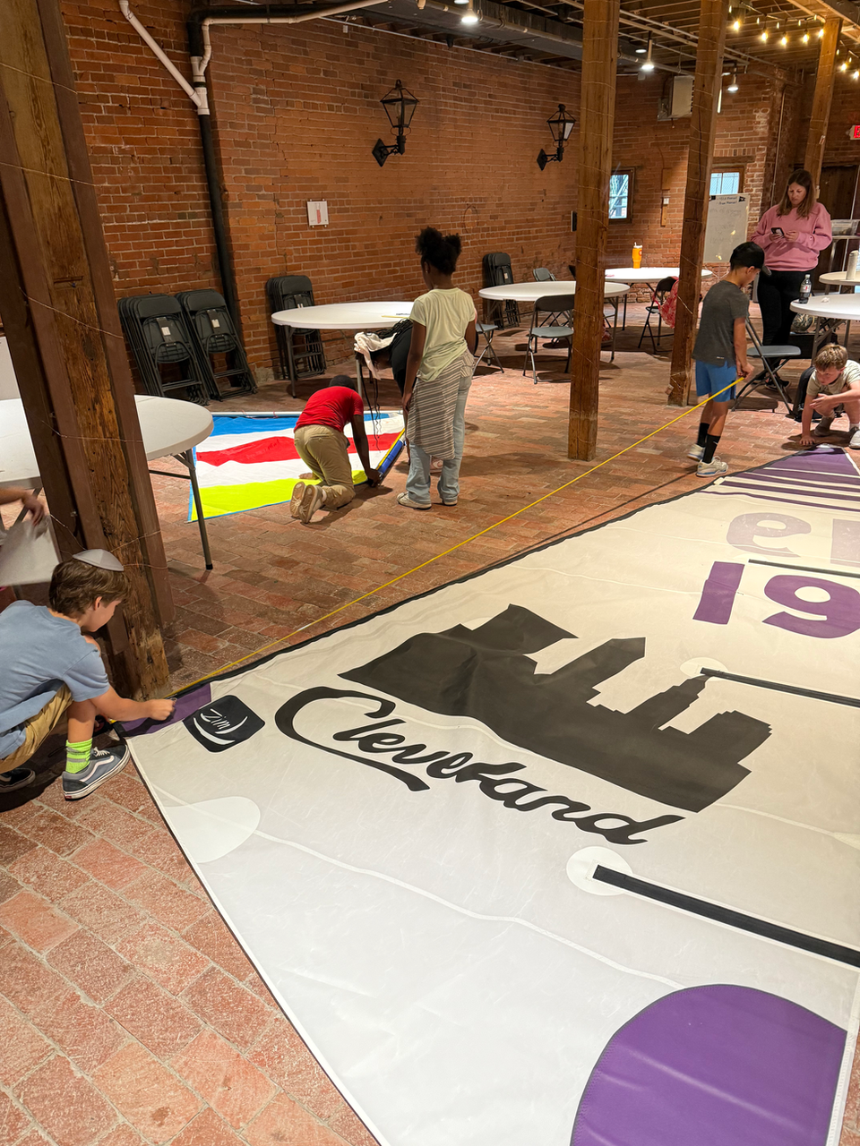 Children painting a large floor map with 'Cleveland' and city skyline