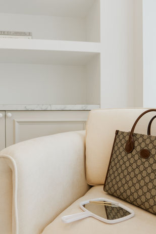 Designer tote bag and hand mirror on a cream armchair