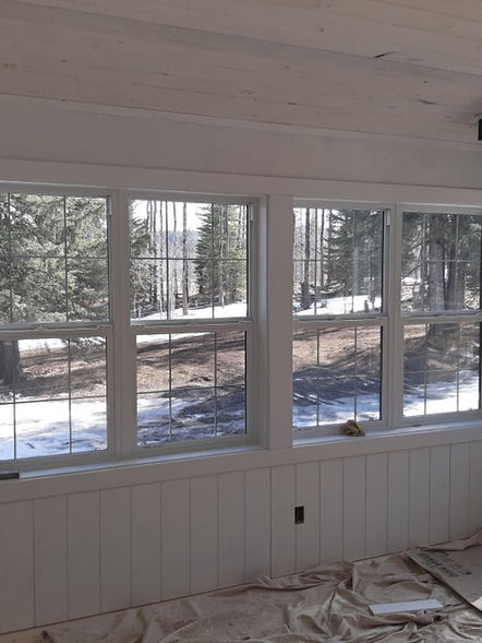 new windows with wood paneling and windowsill looking into the forest