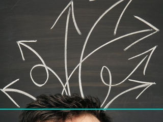 A forehead with dark hair is at the bottom of the image. Above, several chalk-drawn arrows on a blackboard point in different directions, suggesting confusion or decision-making.
