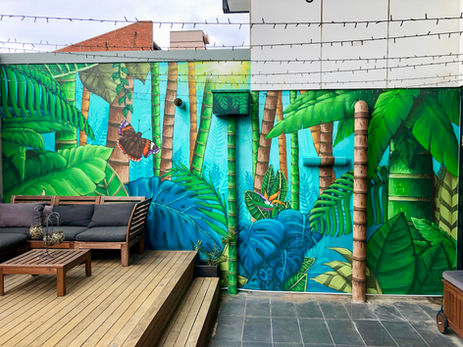 Tropisches Wandgemälde mit Palmen, Blättern und Pflanzen in einem gestalteten Innenhof