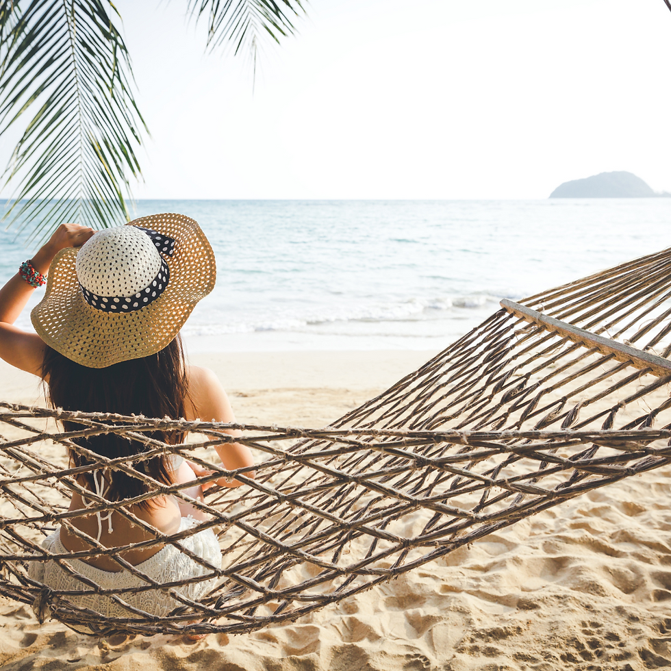 Back of woman with sun hat sitting on side of a hammock on the beach looking out onto the ocean