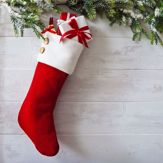 Red stocking stuffer hanging on a wall right below some christmas tree branches