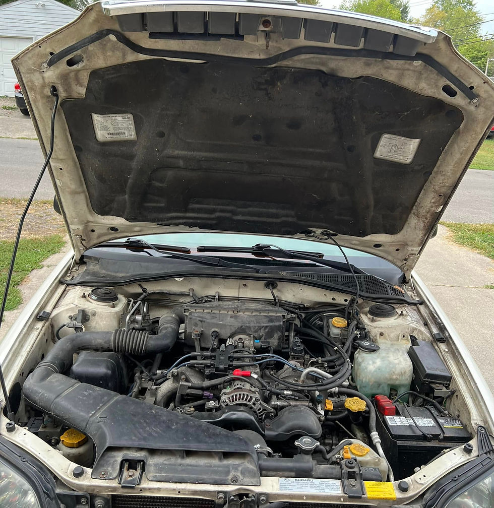 Dusty car engine bay with the hood open before cleaning
