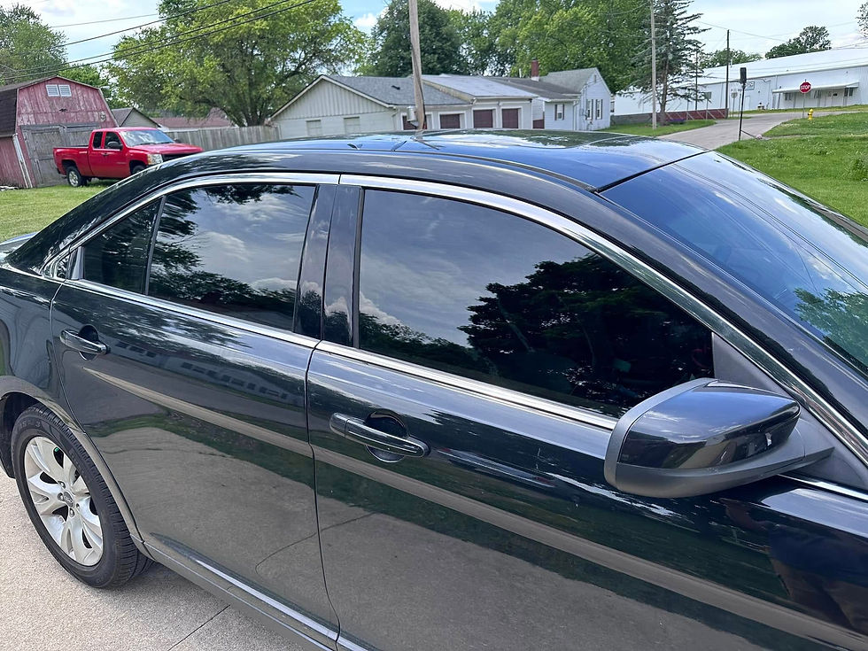 Side profile of a black sedan with dark tinted windows.