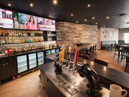 The Gusto Pub sports bar at Gusto Caledon with multiple screens, draft beer taps, and comfortable seating