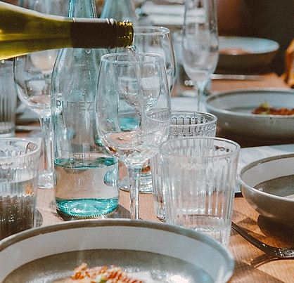 Waiter pouring wine at a dining table with glasses and food served.