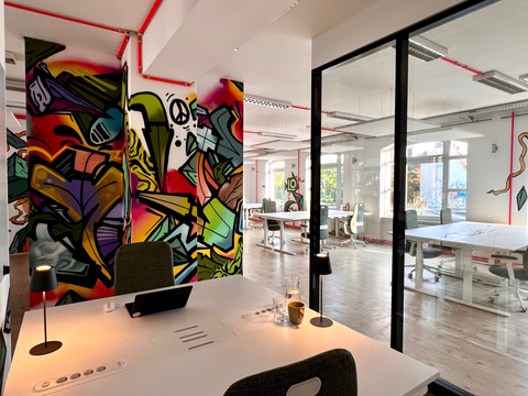 bright coworking desk area with glass meeting room and colorful mural artwork