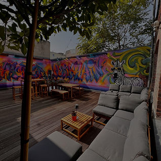 rooftop terrace with lounge seating, wooden tables and vibrant graffiti wall featuring a zebra wearing sunglasses at werkhain