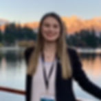 Young woman posing in front of a mountain lake.