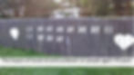 A fence painted with tick marks representing days in lockdown at Level 4 and Live 3 between large hearts
