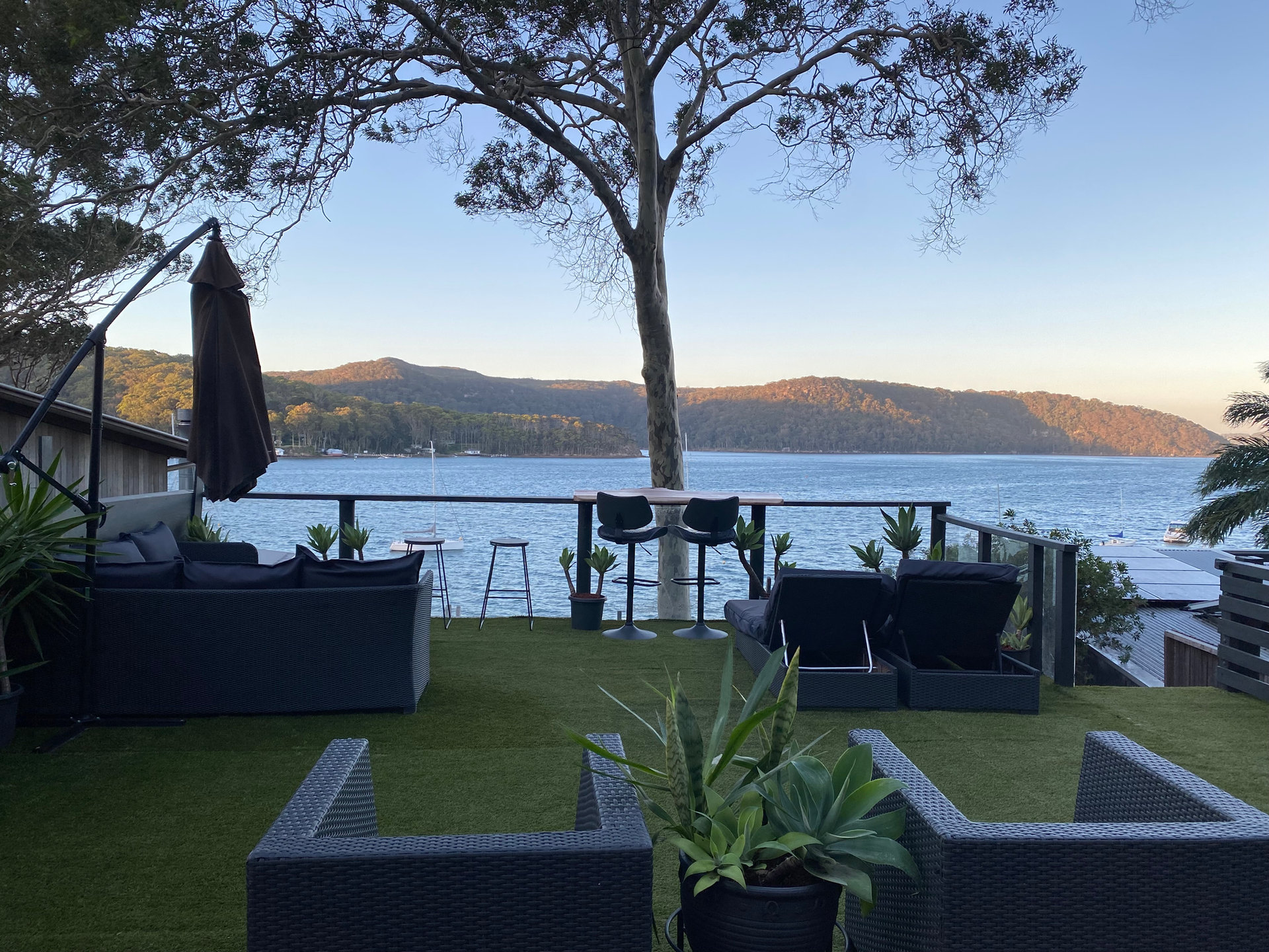 Deck lounge under the angophora tree looking over Pittwater at dusk