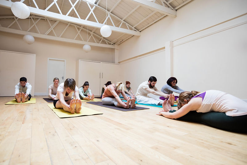 trainer-assisting-group-people-with-pashimottanasana-exercise.jpg
