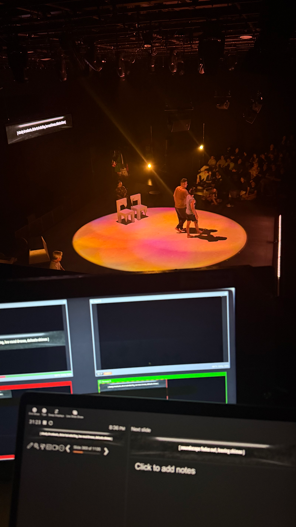 Creative captioning operator’s view of the performers, showing a live theatre performance on stage with captioning monitors in the foreground.